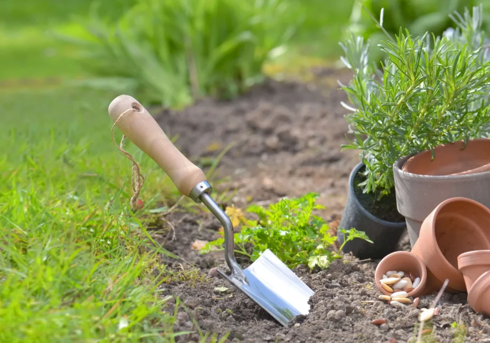 shovel-planted-in-the-soil-of-garden-next-to-flowerpots-min